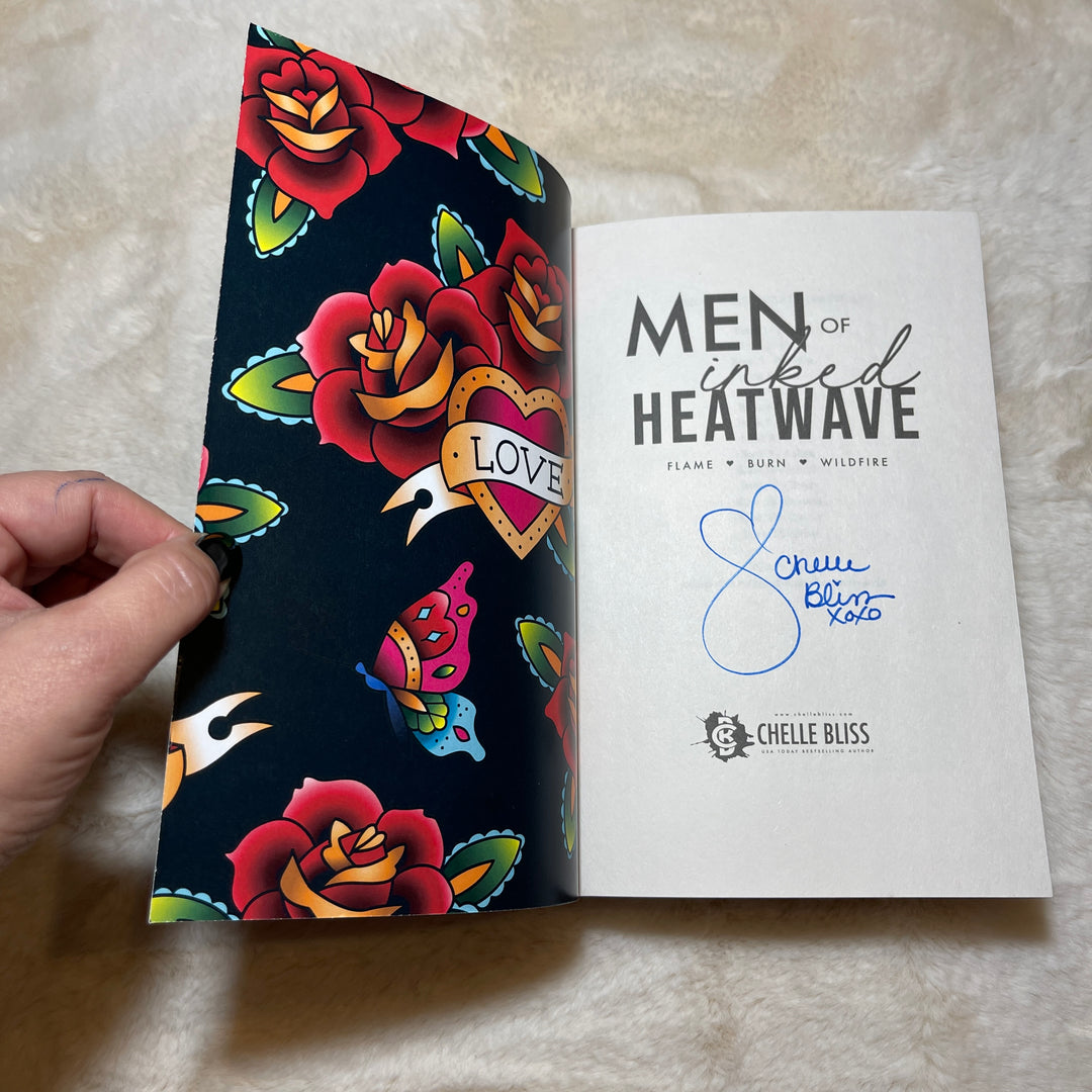 Men of Inked Heatwave Volume 1 paperback book opened to the title page, displaying Chelle Bliss autograph.