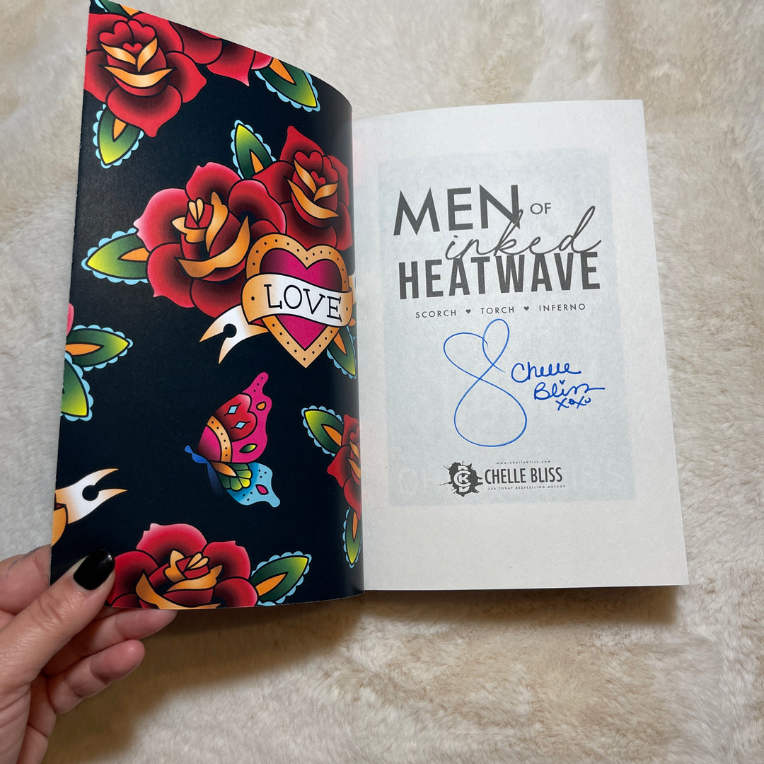 Men of Inked Heatwave Volume 4 Paperback book opened to  the title page with an autograph from Chelle Bliss