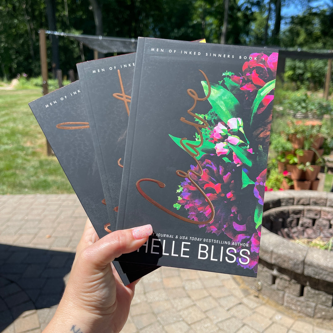 Three books, Crave, Need and Want held by a hand with a garden background