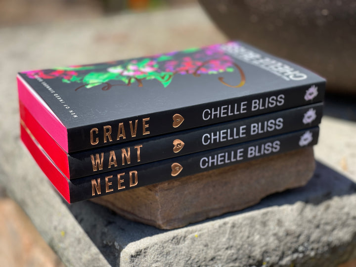 Stack of books Crave, Want and Need by Chelle Bliss on a stone surface