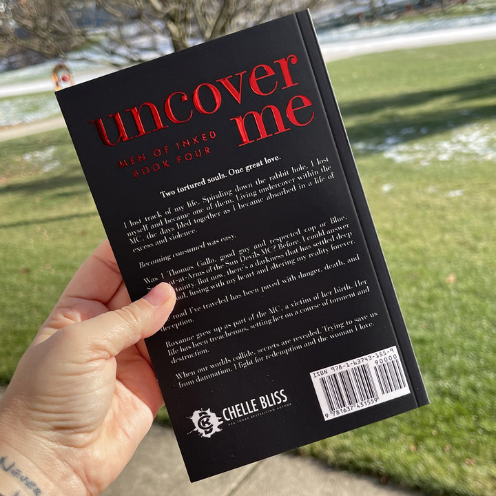 back of paperback book Uncover Me 10th anniversary by Chelle Bliss held in a hand with grass in the background