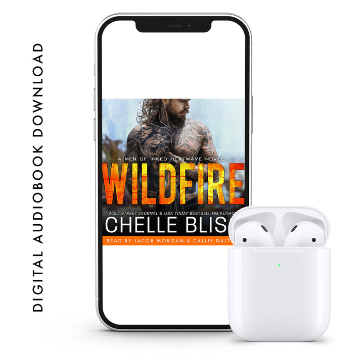 A phone displaying an audiobook cover with the title 'Wildfire' by Chelle Bliss, featuring a man and a woman with a dramatic background. A set of white wireless earbuds are placed next to the phone.