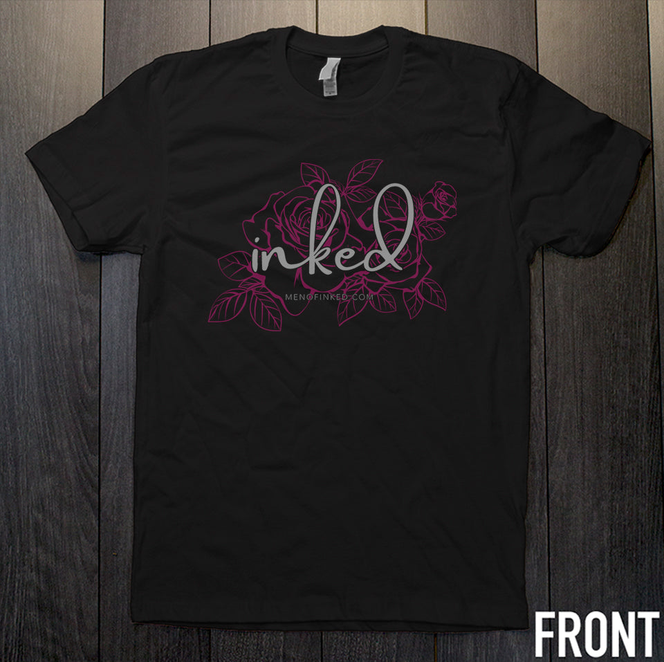 black t-shirt with Inked written on the front in white overtop of pink flowers on a wooden background